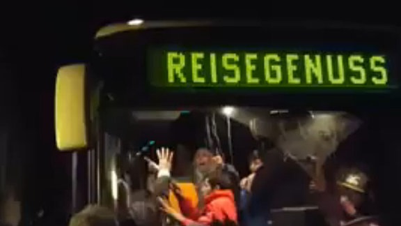 Ein Reisebus mit Flüchtlingen, umringt von Menschen