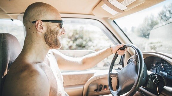 Mann mit Bart und ohne Shirt am Steuer eines Autos (Symbolbild)