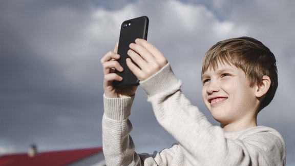 Ein Junge macht mit dem Handy ein Foto von sich